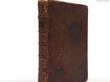 an old book sitting on top of a white table next to a white wall
