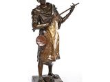 une statue en bronze représentant un homme avec une guitare, posée sur un socle en marbre