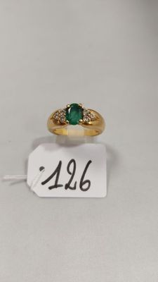 gros plan d'une bague en or avec une pierre verte