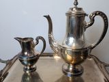 a silver tray with a silver tea pot and a silver cup on it