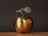 une pomme dorée surmontée d'une feuille
