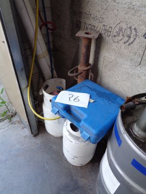 Plusieurs fûts sont alignés contre un mur, chacun muni d'une étiquette indiquant son prix.