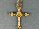 gold plated cross on a gray surface with a coin in the center