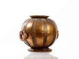 un vase doré posé sur une surface blanche