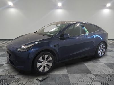 une Tesla Model Y bleue garée dans une pièce au sol à carreaux