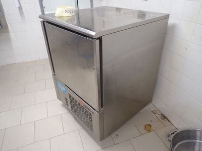 un petit réfrigérateur en acier inoxydable dans un coin de la salle de bains