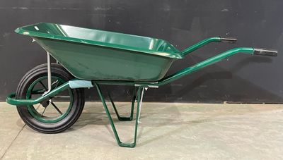 a green wheelbarrow is sitting on a concrete floor