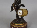 a statue of a cupid holding a clock on a table