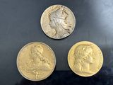 three gold coins sitting on top of a black surface