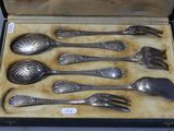 six silver spoons in a box with a spoon and fork
