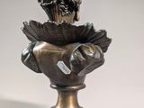 bronze bust of a man holding a bird on a pedestal
