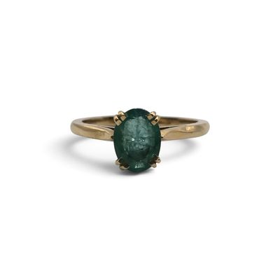 un gros plan d'une bague en or sertie d'une émeraude verte