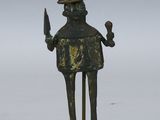 une statue représentant un homme tenant un couteau et portant une couronne sur la tête