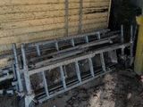 a pile of old metal items outside of a yellow house