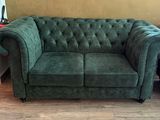a green couch sitting in a living room next to a bed