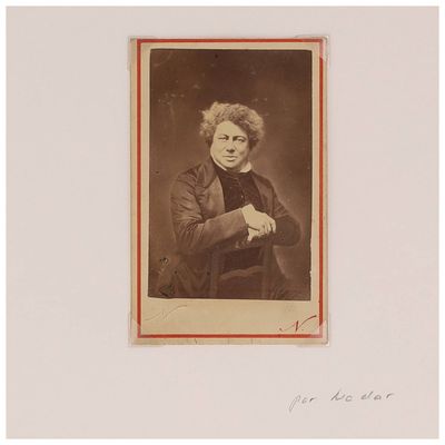 une vieille photo d'une femme aux cheveux bouclés, assise devant une table