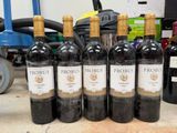 six bottles of red wine are lined up on a table