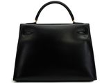 a black leather handbag on a white background with a gold handle