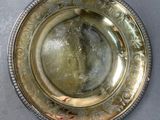 a silver plate with a design on it on a table
