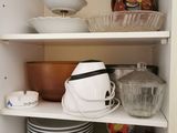 many dishes and bowls on the shelves in the cabinet