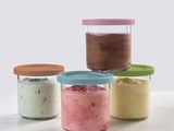 Quatre bocaux garnis de garnitures de différentes couleurs sont posés sur une table