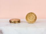 a gold coin sitting on top of a marble slab next to a gold ring