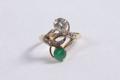 a close up of a diamond and emerald ring on a white surface