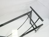 une table en verre surmontée d'un piètement en métal
