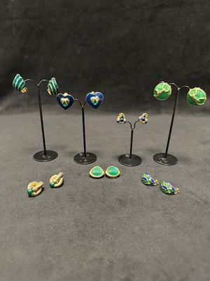 a set of five small green, yellow and blue earrings on black stands