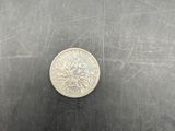 a silver coin sitting on a metal surface next to a black object
