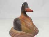 statue d'un canard posé sur un socle, sur une surface blanche
