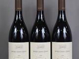 three bottles of red wine are lined up on a glass shelf