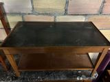 an old wooden table with a glass top sitting on top of a floor