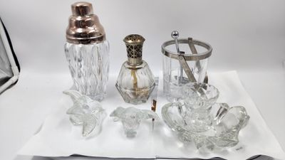 a silverware set on a white table with a silver spoon and a glass shaker