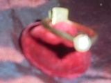 une bague en or sertie d'une perle, posée sur un écrin rouge