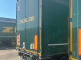 two green semi trucks parked next to each other in a parking lot