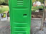 des toilettes portables vertes posées au milieu d'un terrain en gravier