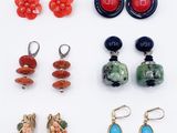 several pairs of earrings and rings are arranged on a white surface