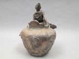 bronze statue of a woman sitting on top of a vase