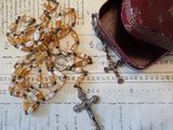 a rosary, a hat, and a book on a table