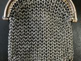 a silver chainmail purse with pearls hanging from it