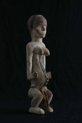 une statue en bois représentant un homme tenant un oiseau, sur fond noir