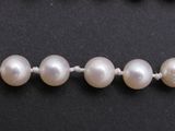a close up of a strand of white pearls on a black surface