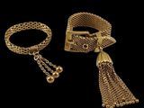two gold bracelets and a bracelet with a tassel on a black background