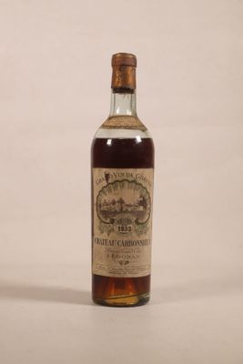 une vieille bouteille de whisky posée sur une surface blanche