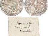 two silver coins with a piece of paper on top of it