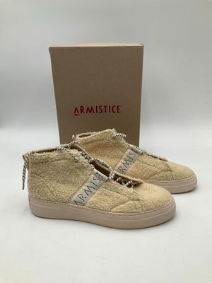 une paire de baskets beiges avec une chaîne sur le côté