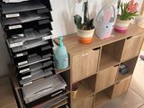 a stack of files sitting on a shelf next to a plant