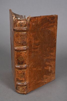 an old book with a leather cover sitting on top of a table