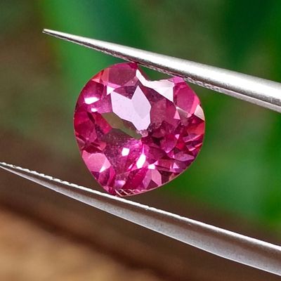 a close up of a pink diamond being held by a pair of pliers